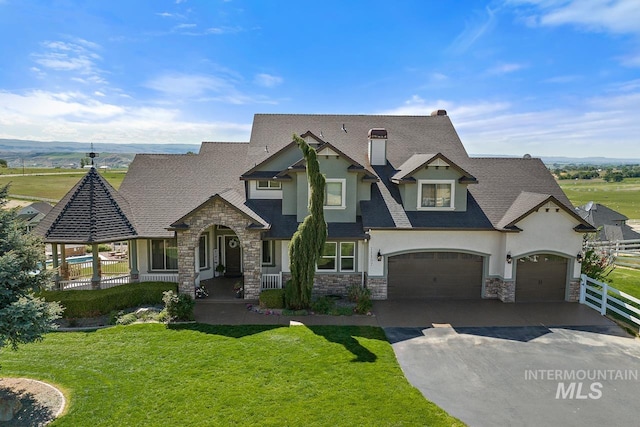 view of front of property with driveway, stone siding, stucco siding, an attached garage, and a front yard