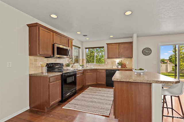 11422 W Darkwood St, Star, ID 83669 - kitchen with black appliances, a center island, healthy amount of natural light, dark wood-style floors, and recessed lighting
