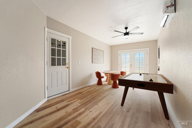 5217 Weston Ave, Caldwell, ID 83607 - rec room featuring a textured wall, an AC wall unit, a ceiling fan, light wood-style flooring, and french doors