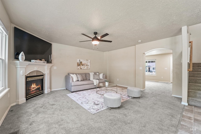 5217 Weston Ave, Caldwell, ID 83607 - carpeted living area with arched walkways, ceiling fan, a fireplace, stairs, and a textured ceiling