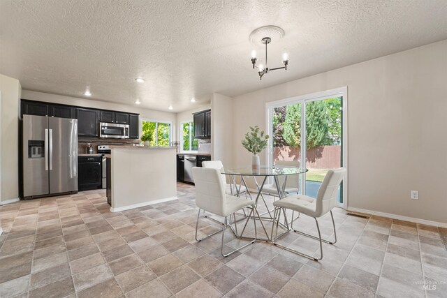 5217 Weston Ave, Caldwell, ID 83607 - dining room with a textured ceiling, a chandelier, recessed lighting, and light stone finish flooring