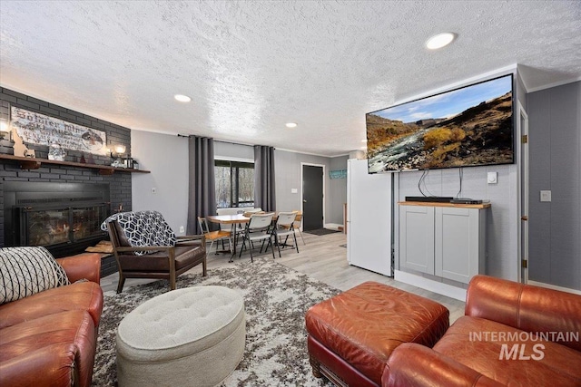 living room with a textured ceiling, a fireplace, and light hardwood / wood-style flooring