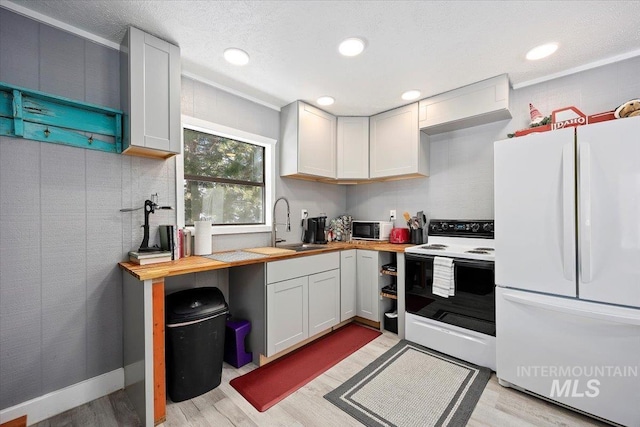 kitchen featuring white cabinetry, butcher block countertops, white appliances, and sink