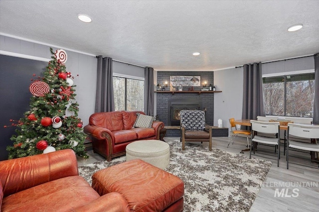 living room with a brick fireplace, hardwood / wood-style floors, and a textured ceiling