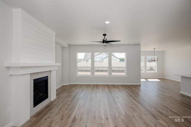 8172 E Red Horse St, Nampa, ID 83687 - unfurnished living room featuring a fireplace, light wood-style flooring, a ceiling fan, baseboards, and a chandelier