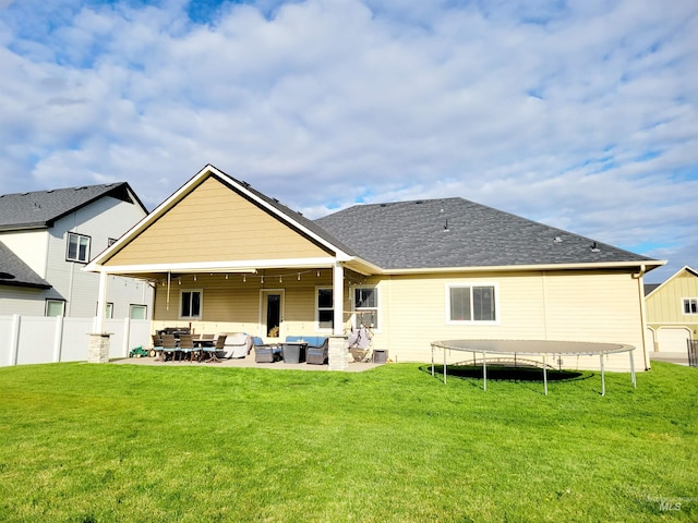 rear view of property featuring a patio, outdoor lounge area, a trampoline, and a lawn