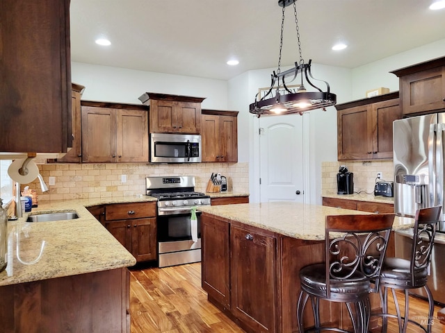 kitchen featuring appliances with stainless steel finishes, tasteful backsplash, light hardwood / wood-style floors, and a center island