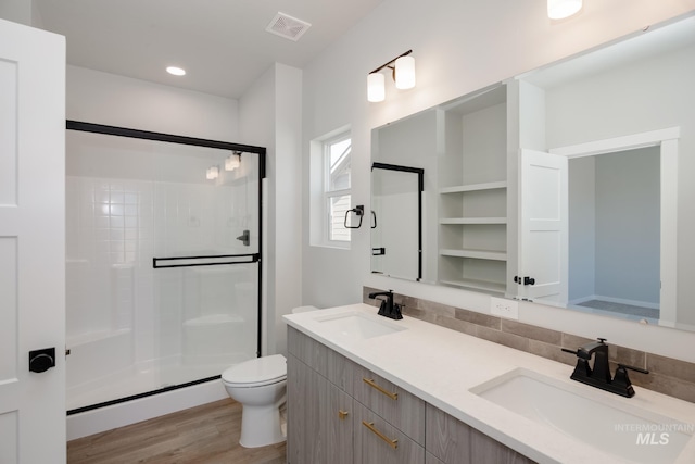 bathroom with hardwood / wood-style flooring, backsplash, vanity, a shower with shower door, and toilet