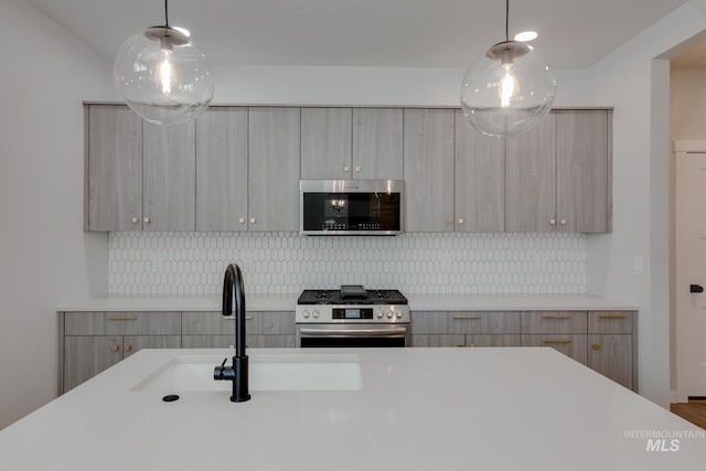 kitchen featuring decorative backsplash, appliances with stainless steel finishes, hanging light fixtures, and sink