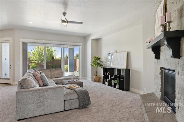 carpeted living room featuring baseboards, a glass covered fireplace, and ceiling fan