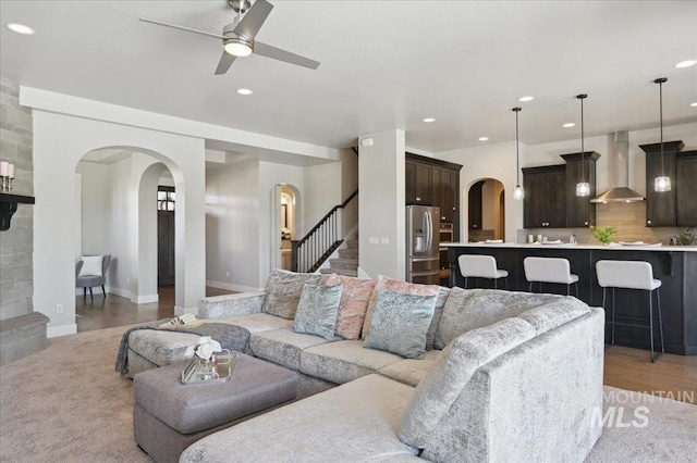 living room featuring arched walkways, baseboards, recessed lighting, stairs, and ceiling fan