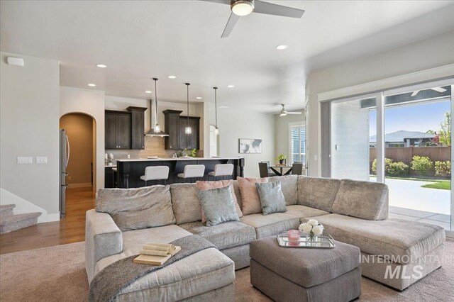 living room with arched walkways, recessed lighting, a ceiling fan, wood finished floors, and stairway