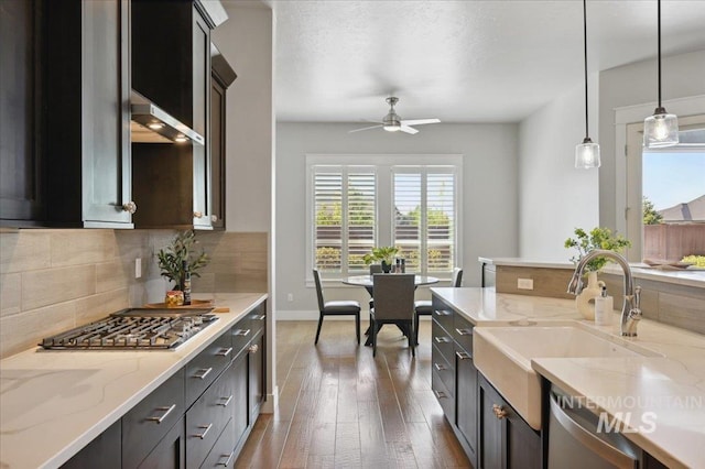 kitchen with stainless steel appliances, a sink, tasteful backsplash, hardwood / wood-style flooring, and hanging light fixtures