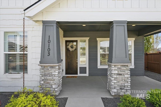 view of exterior entry with fence and covered porch