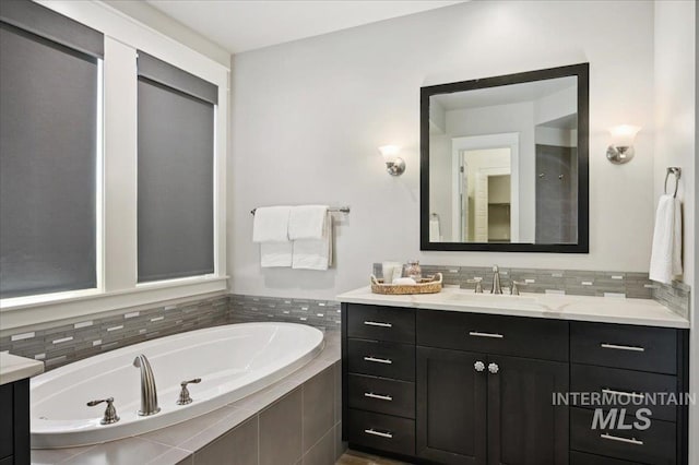 bathroom with decorative backsplash, a garden tub, and vanity