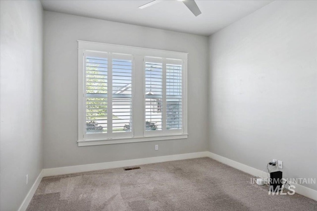 carpeted spare room with plenty of natural light, baseboards, visible vents, and ceiling fan