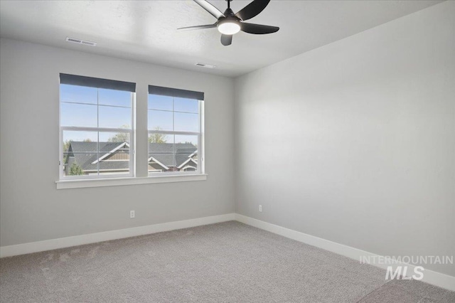 carpeted spare room featuring visible vents, a ceiling fan, and baseboards