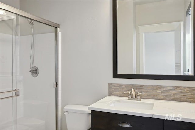 full bathroom featuring toilet, vanity, backsplash, and a stall shower