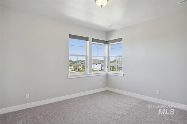 carpeted spare room with visible vents and baseboards