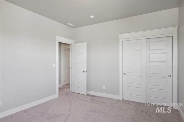 unfurnished bedroom featuring baseboards, carpet floors, and a closet