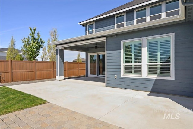 rear view of property featuring fence, a ceiling fan, and a patio