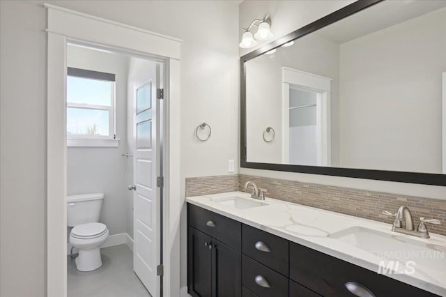 bathroom featuring toilet, a sink, and tasteful backsplash