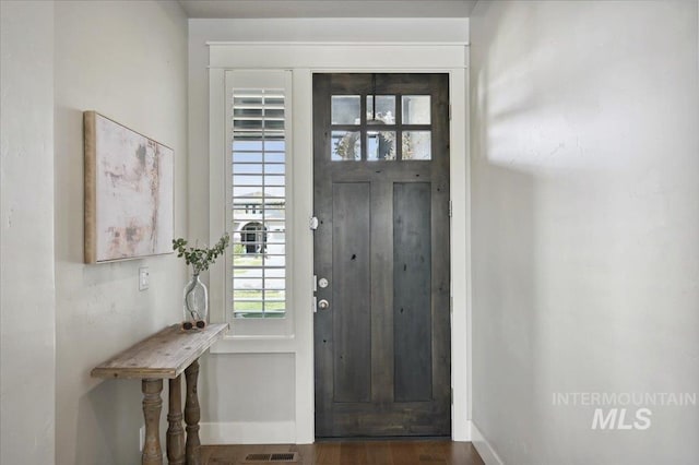 foyer entrance featuring visible vents, wood finished floors, and baseboards