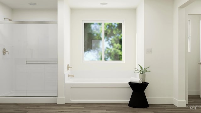 bathroom with a garden tub, a shower stall, baseboards, and wood finished floors