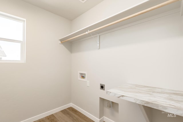 laundry area featuring electric dryer hookup, washer hookup, wood finished floors, baseboards, and laundry area