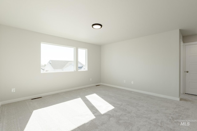 empty room featuring visible vents, baseboards, and light carpet