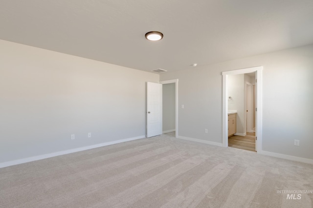 unfurnished bedroom featuring visible vents, baseboards, light colored carpet, and connected bathroom