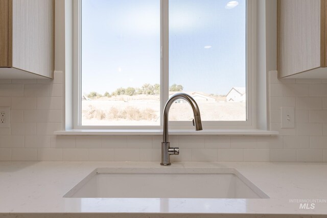 details featuring light stone counters, backsplash, and a sink