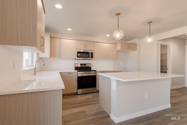 kitchen with a center island, light countertops, light wood-style flooring, stainless steel appliances, and a sink