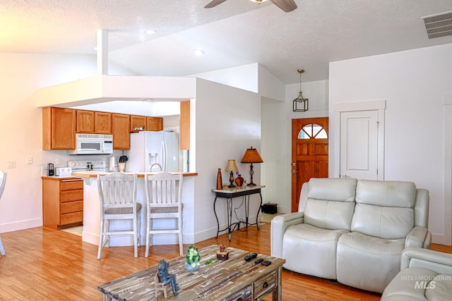 living room with a ceiling fan, visible vents, baseboards, lofted ceiling, and light wood-style floors