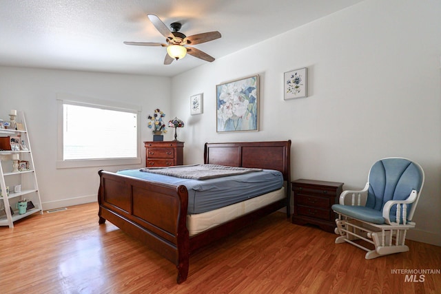 bedroom with baseboards, ceiling fan, and light wood-style flooring