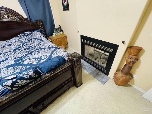 bedroom featuring light colored carpet and a multi sided fireplace