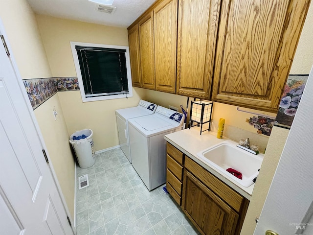 clothes washing area with cabinets, separate washer and dryer, and sink