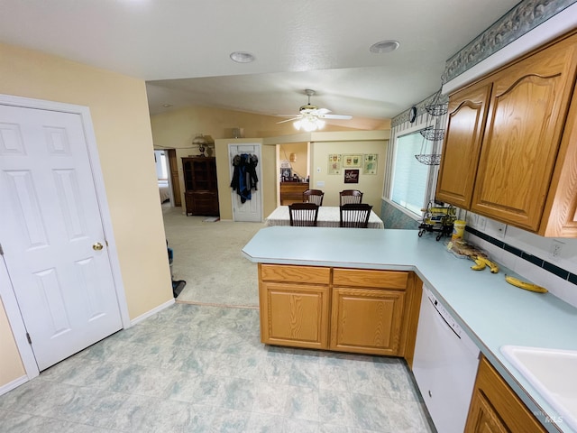 kitchen with sink, white dishwasher, light carpet, vaulted ceiling, and kitchen peninsula