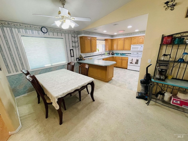 kitchen featuring lofted ceiling, sink, light colored carpet, kitchen peninsula, and white appliances