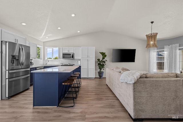 5174 N Rothmans Ave, Boise, ID 83713 - kitchen featuring stainless steel appliances, lofted ceiling, white cabinetry, a breakfast bar, and a center island