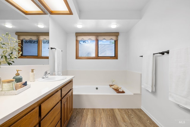 bathroom featuring a garden tub, wood finished floors, and vanity