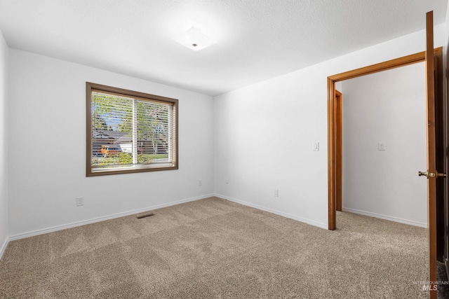 carpeted spare room featuring baseboards and visible vents