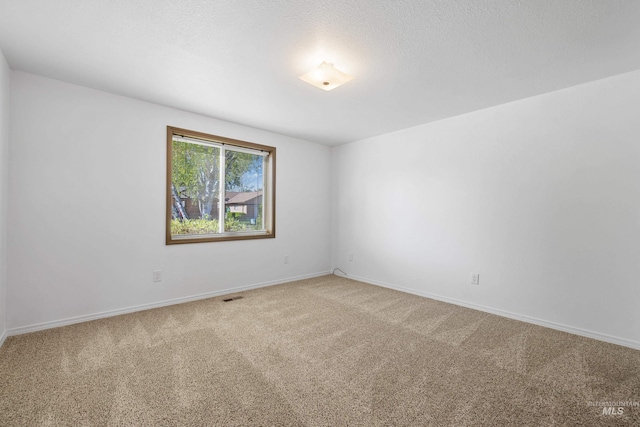 carpeted empty room featuring visible vents and baseboards