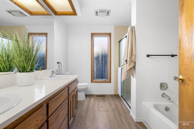 full bath featuring wood finished floors, a sink, toilet, an enclosed shower, and visible vents
