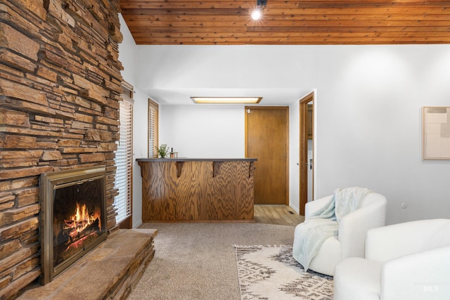 living room featuring wood ceiling, carpet floors, and a stone fireplace