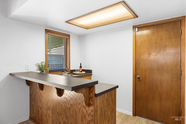 office area with light wood-type flooring, a dry bar, and baseboards