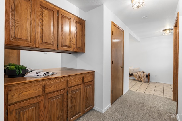 interior space featuring light tile patterned flooring, baseboards, and light colored carpet