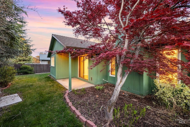 back of house with a patio area, a lawn, a shingled roof, and fence