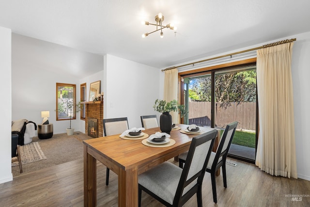 dining room with light wood-style flooring, baseboards, a fireplace, and a notable chandelier