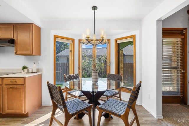 dining space with light wood finished floors, baseboards, and a notable chandelier
